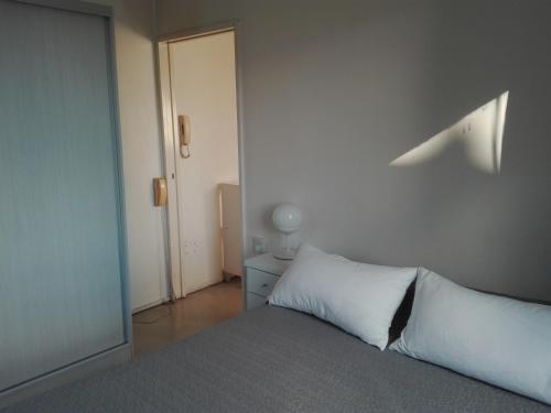 1 dormitorio con cama con almohada blanca y puerta en Esmeralda Vista en Buenos Aires