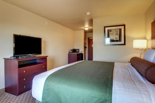 a hotel room with a bed and a flat screen tv at Cobblestone Hotel & Suites - Charlestown in Charlestown