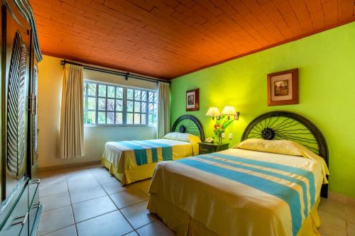Duas camas num quarto com paredes amarelas e verdes em Hotel Chichen Itza em Chichén Itzá