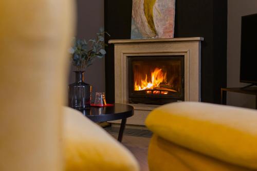 a living room with a fireplace with a chair and a table at Barba Boutique Hotel in Korçë