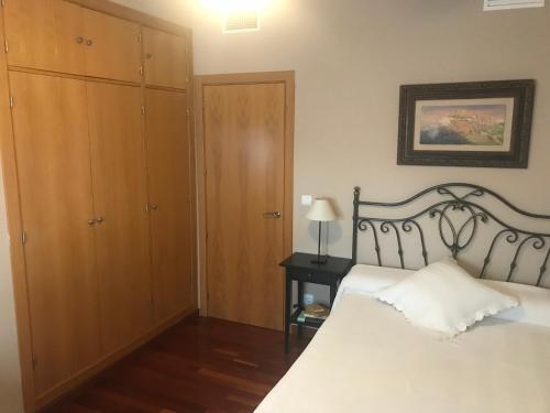 a bedroom with a white bed and a wooden cabinet at Habitación doble independiente con baño compartido in Granada