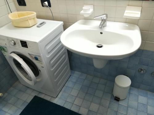 a bathroom with a washing machine and a sink at LA CASA DI MARZIA in Bardolino