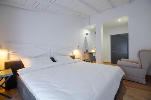 a bedroom with a large white bed and a chair at Barba Boutique Hotel in Korçë
