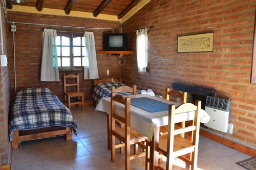 Cette chambre comprend deux lits, une table et des chaises. dans l'établissement Complejo de Cabañas Tierra Nuestra, à Mina Clavero