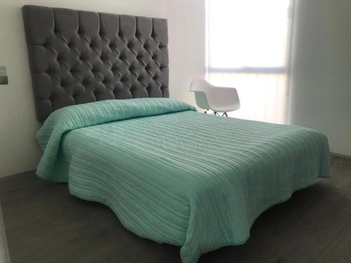 1 cama con colcha verde y silla blanca en Comodo apartamento Ciudad de Mexico, en Ciudad de México