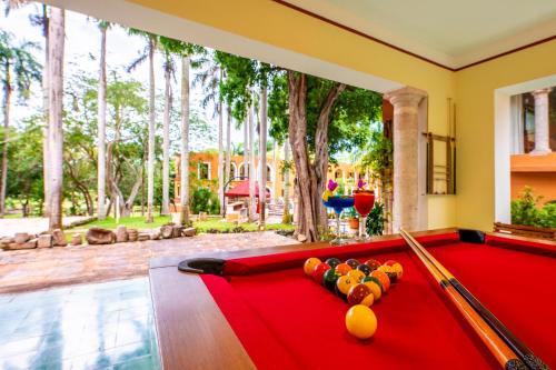 a pool table with balls on it in a room with trees at Hacienda Uxmal Plantation & Museum in Uxmal