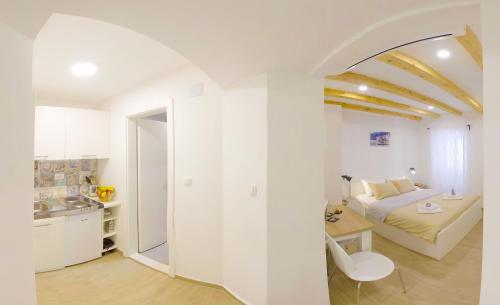a white room with a bed and a kitchen at The Little Gem in Komiža