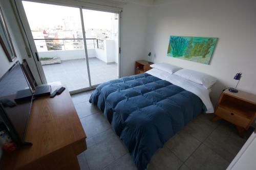 sypialnia z dużym łóżkiem i niebieskim kocem w obiekcie Ático Palermo w BuenosAires