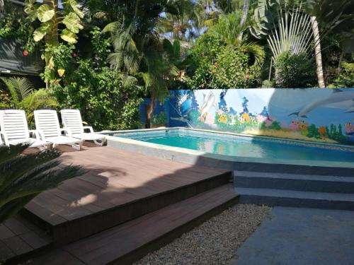 a swimming pool with two white chairs next to it at Casa Brisa Mar Hotel in Las Terrenas