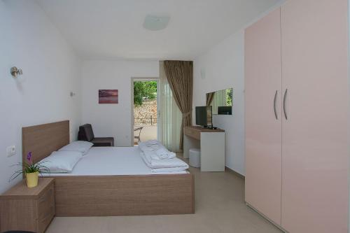 1 dormitorio con cama, escritorio y nevera en Apartments Villa Aquamarine, en Duće