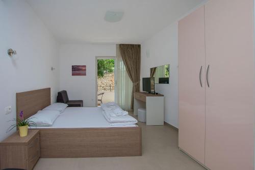 a bedroom with a bed and a desk and a refrigerator at Apartments Villa Aquamarine in Duće