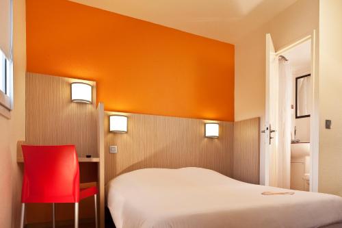 a bedroom with a bed and a red chair at Première Classe Perpignan Nord in Rivesaltes