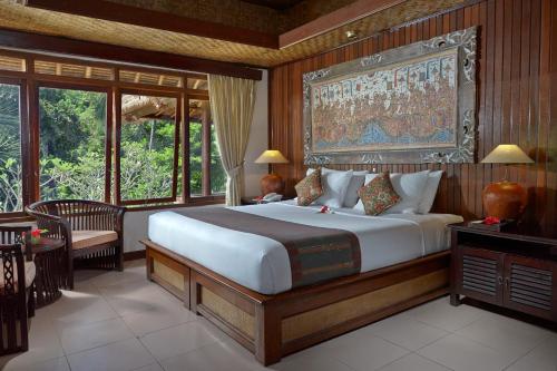 a bedroom with a large bed with a large painting on the wall at Hotel Tjampuhan Spa in Ubud