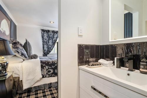 a bathroom with a sink and a bed and a mirror at Battery Point Boutique Accommodation in Hobart