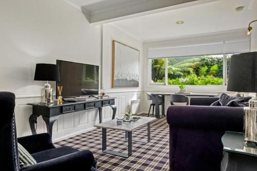 a living room with two couches and a tv at Battery Point Boutique Accommodation in Hobart