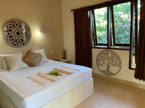 a bedroom with a large white bed with windows at Villa Anjing in Nusa Dua
