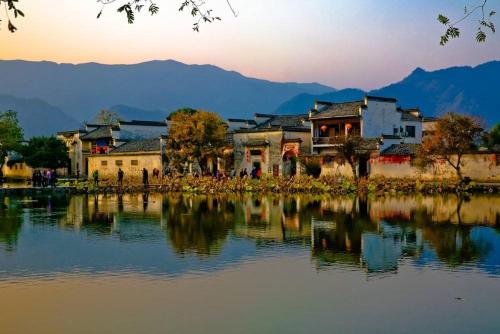 a group of buildings next to a body of water at Xishan Wutong Qinyuan (Free Pick up Service) in Huangshan