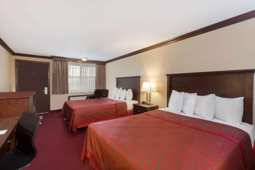 a hotel room with two beds and a desk at Days Inn by Wyndham Auburn in Auburn