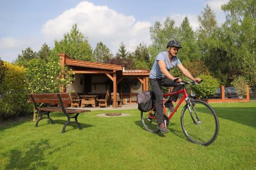 a man riding a bike in the grass near a bench at Apartamenty i Domki Osińscy in Braniewo