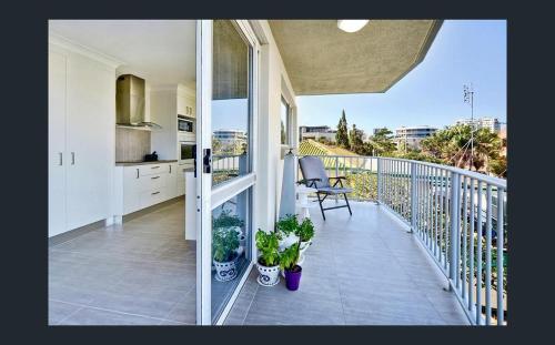 a balcony with two potted plants and a kitchen at Kings Beach Retreat in Caloundra