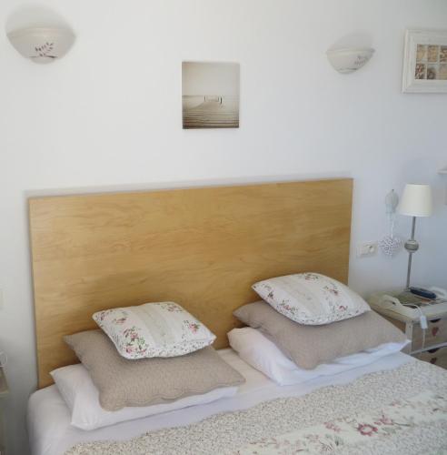 a bed with a wooden headboard and two pillows at Hôtel Les Embruns Sables d'Olonne in Les Sables-dʼOlonne