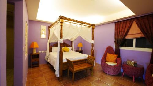 鵝鑾的住宿－龍園居民宿，一间卧室配有一张天蓬床和两把椅子