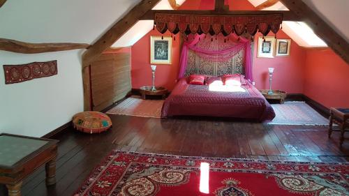 1 dormitorio en el ático con 1 cama con dosel rojo en le jardin des chênes, en Plumelec