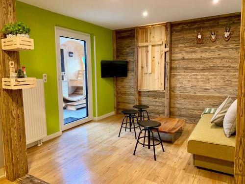 sala de estar con paredes verdes, sofá y taburetes en Boutique Appartments AlteGreißlerei en St. Wolfgang