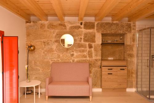 a living room with a chair and a stone wall at Casa Choupas in Cangas de Morrazo