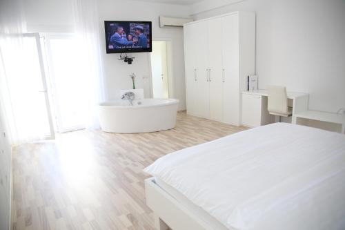 a white bedroom with a bed and a tv on the wall at Apartments Barbati in Novalja