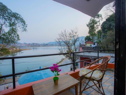 a balcony with a table and chairs and a view of a river at Hotel Fewa Corner & Restro in Pokhara