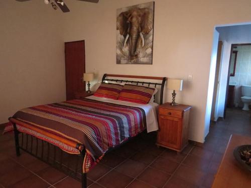 una camera da letto con un letto con un'immagine a parete di elefante di Crowe's Nest a Marloth Park