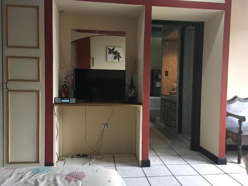 ein Wohnzimmer mit einem TV und ein Schlafzimmer in der Unterkunft Apartamento Central Xelajú in Quetzaltenango