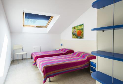 two beds in a room with white walls and blue shelves at Appartamenti Palmaria in Diano Marina