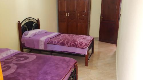 two beds in a room with purple sheets at Faridi vacancy appartment in Casablanca