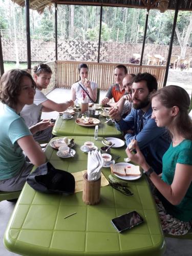 Un grupo de personas sentadas alrededor de una mesa comiendo comida en Kaziranga Eco Camp, en Hatikhuli