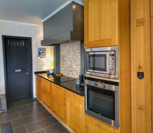 uma cozinha com armários de madeira e um micro-ondas em The White Door em Aalst