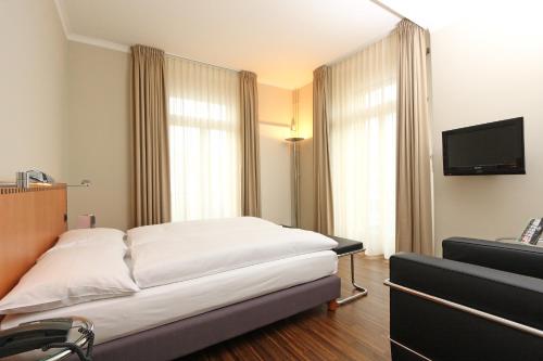 a hotel room with a bed and a flat screen tv at Art Déco Hotel Elite in Biel