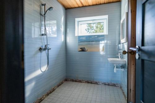 La salle de bains est pourvue d'une douche et d'un lavabo. dans l'établissement Mere Puhkemaja, à Kungla