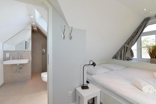 - une chambre blanche avec un lit et une salle de bains dans l'établissement Gilde Hus, à Westerland
