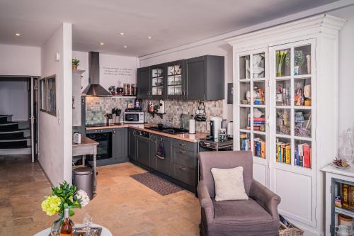 une cuisine avec des armoires noires et une chaise dans l'établissement Maison Vaison, à Vaison-la-Romaine