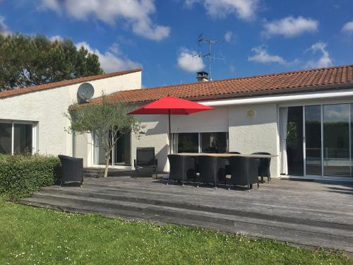 patio ze stołami i krzesłami oraz czerwonym parasolem w obiekcie Modern villa with private pool w mieście Brives-sur-Charente
