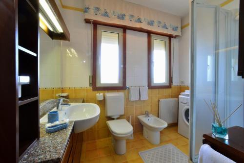 ein Badezimmer mit einem Waschbecken, einem WC und einem Waschbecken in der Unterkunft Condominio Al Cigno in Lignano Sabbiadoro