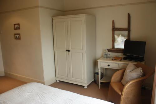 a bedroom with a bed, chair and a television at Driftwood in Porthscatho