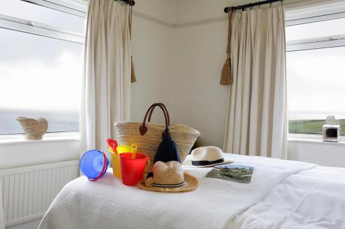 a bed with hats and other items on it at Driftwood in Porthscatho