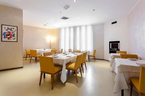 a dining room with white tables and yellow chairs at Grand Hotel President in Spilimbergo