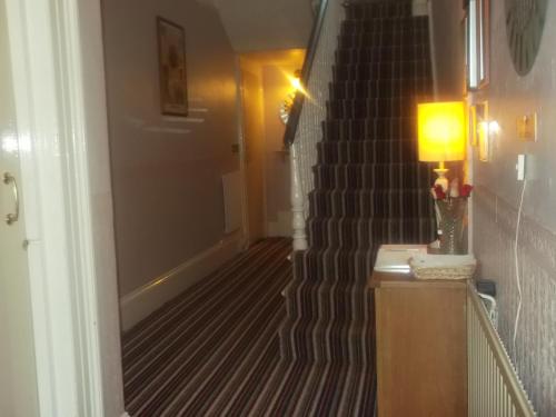 a hallway with a staircase with a lamp on a table at Ashfield Guest House in Torquay