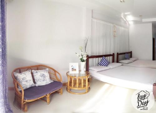 a room with two beds and a chair and a table at Lay Day in Khon Kaen