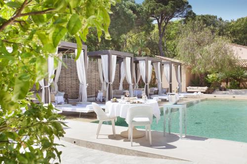 uma área de refeições com uma mesa e cadeiras ao lado de uma piscina em MUSE Saint Tropez - Small Luxury Hotels of the World em Saint-Tropez