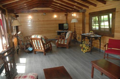 una sala de estar con sillas y TV en una cabaña en Hotel Rural El Texu, en Arriondas